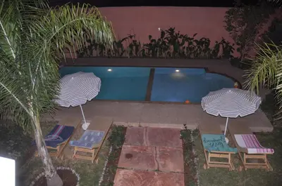two umbrellas and chairs next to a swimming pool at Jolie villa moderne avec piscine privée. in Marrakech
