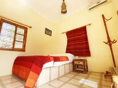a bedroom with a bed and a cross on the wall at Guest House Defat Kasbah in Aït Ben Haddou