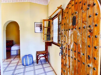 a large wooden door in a room with a table at Guest House Defat Kasbah in Aït Ben Haddou