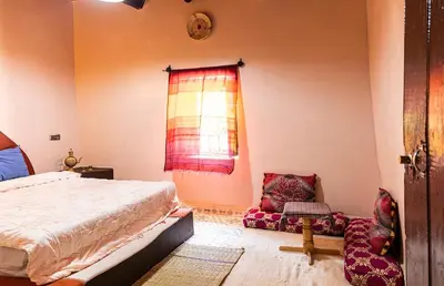 a bedroom with a bed and a window and a chair at Dar Jamila in Achbarou