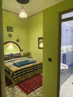 a bedroom with green walls and a bed and a sink at Appartement moha merzouga in Merzouga