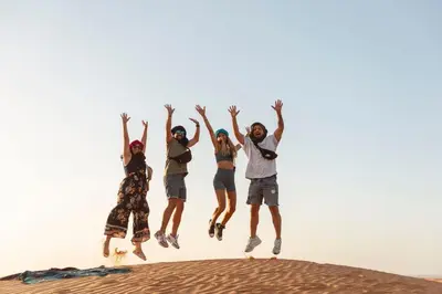 a group of people jumping in the desert at Appartement moha merzouga in Merzouga