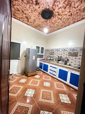 a kitchen with a refrigerator and a tile floor at Appartement moha merzouga in Merzouga
