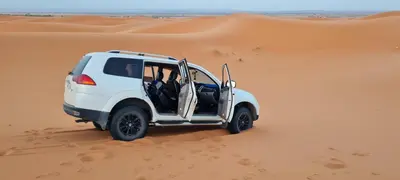 a white jeep driving through the desert at Appartement moha merzouga in Merzouga