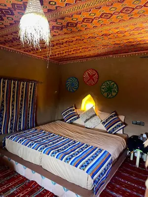 a bedroom with a bed with a wooden ceiling at Aladdin Desert Lodge - Mhamid Sahara Camp in El Gouera