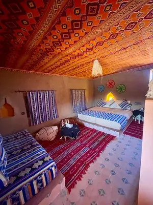 two beds in a room with a wooden ceiling at Aladdin Desert Lodge - Mhamid Sahara Camp in El Gouera