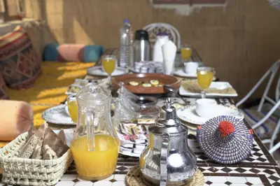 a table with a black and white checkered table cloth with orange juice at Aladdin Desert Lodge - Mhamid Sahara Camp in El Gouera