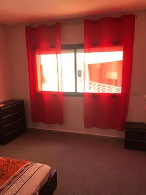 a bedroom with red curtains and a bed and a window at Chez ZAKARIA de Lyon in Meknès