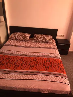 a bedroom with a bed with a red comforter at Chez ZAKARIA de Lyon in Meknès