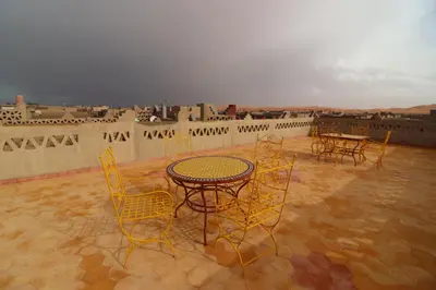 a patio with tables and chairs on a roof at Riad Moha in Merzouga