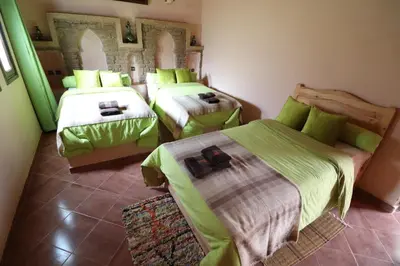 a room with three beds in a room at Riad Moha in Merzouga