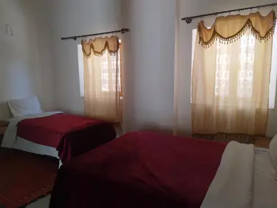 a room with two beds and two windows with curtains at Hotel et Restaurant Riad Amodou in Tinerhir
