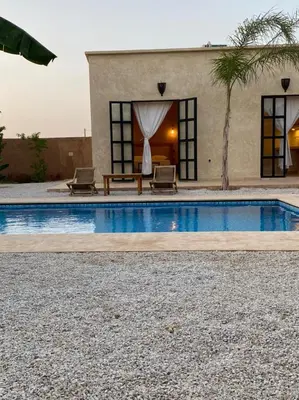 a house with a pool with two chairs and a table at Dar Mamoun in Marrakech