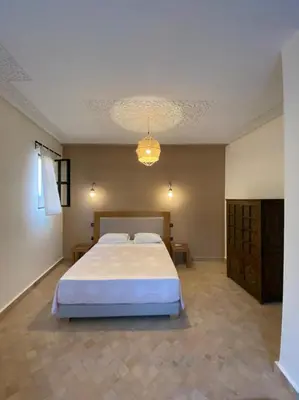 a bedroom with a large bed and a chandelier at Dar Mamoun in Marrakech