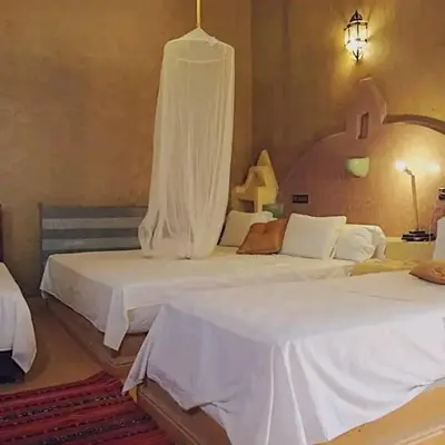 a bedroom with two beds with white sheets at Riad Dar Ouzine in Merzouga