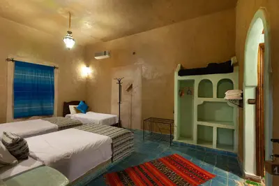 a bedroom with two beds and a bunk bed at Riad Dar Ouzine in Merzouga