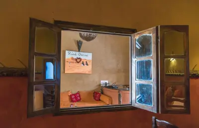 a mirror on a wall with a couch in a room at Riad Dar Ouzine in Merzouga