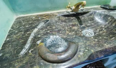 a dirty bathroom sink with a sausage on it at Riad Dar Ouzine in Merzouga