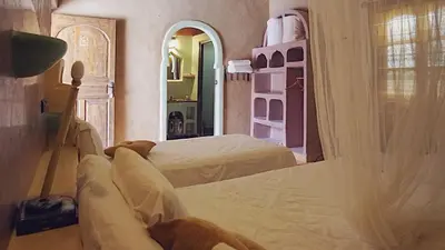 a bedroom with two beds and a mirror at Riad Dar Ouzine in Merzouga