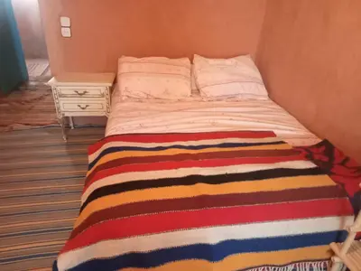 a bed in a room with a striped blanket on it at auberge restau tombouctou in Aït Ben Haddou