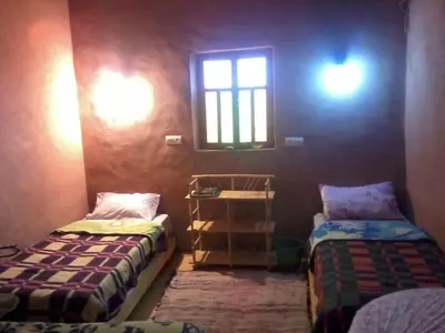 a small room with two beds and a window at auberge restau tombouctou in Aït Ben Haddou
