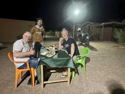 a group of people sitting at a table at night at Café restaurante shelter calm life in Bou Dib