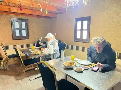 two people sitting at a table eating food at Café restaurante shelter calm life in Bou Dib