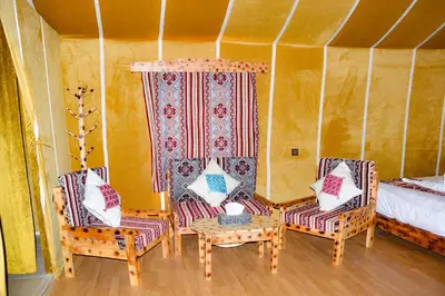 a room with two chairs and a bed at Relaxing Desert Camp in Merzouga
