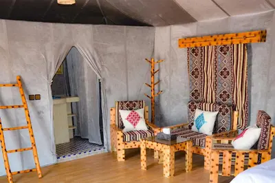 a room with two chairs and a table and a bed at Relaxing Desert Camp in Merzouga