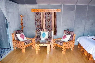 a bedroom with two chairs and a bed and a table at Relaxing Desert Camp in Merzouga