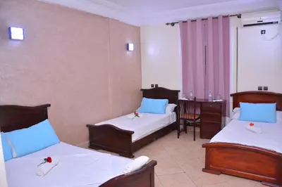 a hotel room with two beds and a desk at Hôtel Elfekri in Er Rachidia