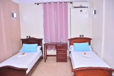 two beds in a room with a table and two beds sidx sidx sidx at Hôtel Elfekri in Er Rachidia