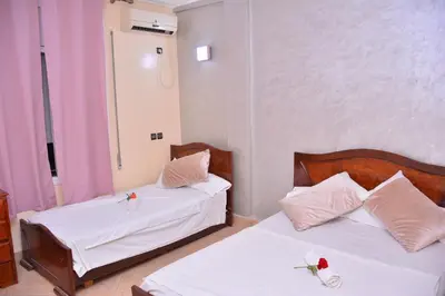 two beds in a room with white sheets and white pillows at Hôtel Elfekri in Er Rachidia