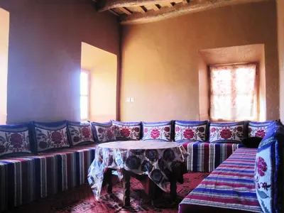 a living room with a couch with a table at Casbah d'hôte La Jeanne Tourisme Ecologique in Boumalne