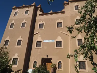a large tan building with a sign on it at Casbah d'hôte La Jeanne Tourisme Ecologique in Boumalne