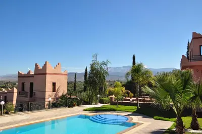 a villa with a swimming pool in front of a house at Le Beau Site Ourika in Aghmat