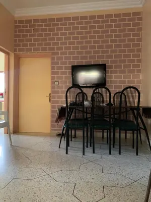 a dining room with a table and chairs in front of a brick wall at Ferme fes in Fès