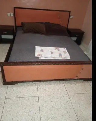 a bed with a wooden headboard with a blanket on it at Ferme fes in Fès