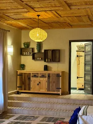 a living room with a chandelier and a wooden cabinet at Kasbah Hnini in Igdourane