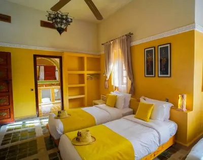two beds in a room with yellow walls at Kasbah Hnini in Igdourane