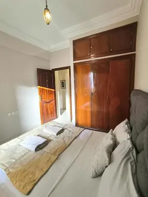 a bedroom with a large bed with a wooden cabinet at Darkoum votre appartement in Fès