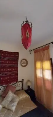 a bedroom with a bed and a window and a chandelier at Riad lala zakia in Moulay Idriss Zerhoun