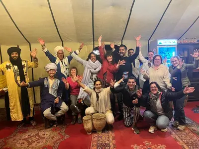 a group of people posing for a picture with their hands in the air at Moda Camp merzouga tours Quad Sunboarding ATV in Merzouga