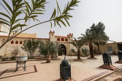 a courtyard with palm trees and a building at Moda Camp merzouga tours Quad Sunboarding ATV in Merzouga