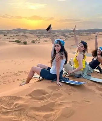 a group of women sitting in the desert at Moda Camp merzouga tours Quad Sunboarding ATV in Merzouga