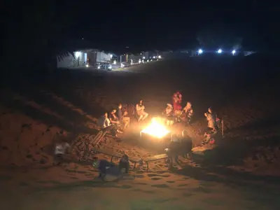 a group of people sitting around a fire at night at Moda Camp merzouga tours Quad Sunboarding ATV in Merzouga