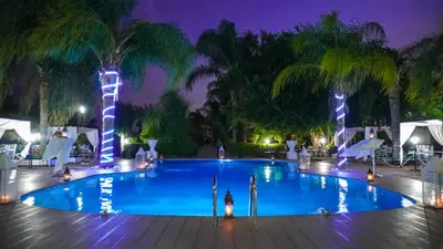 a large swimming pool with blue lights and palm trees at Weedan Hôtel&Spa Marrakech in Oulad Snaguia