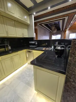 a kitchen with white cabinets and a black counter top at ZR Comfort Delux in Fès