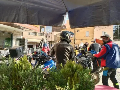 a man standing under an umbrella next to a motorcycle at Hôtel Imilchil in Midelt