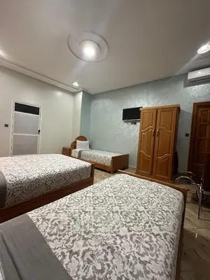 a bedroom with two beds and a cabinet and a tv at Hôtel Imilchil in Midelt